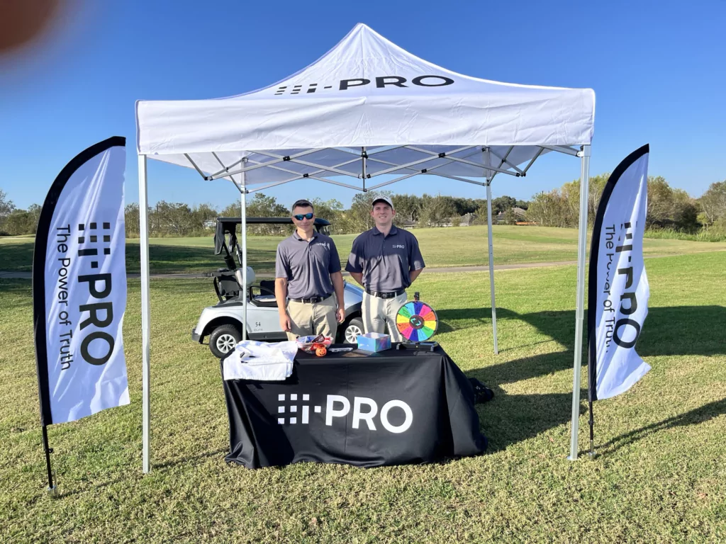 Golf-course booth under a custom event tents 10x10 with branded table cover and feather flags—sampling and fan engagement.