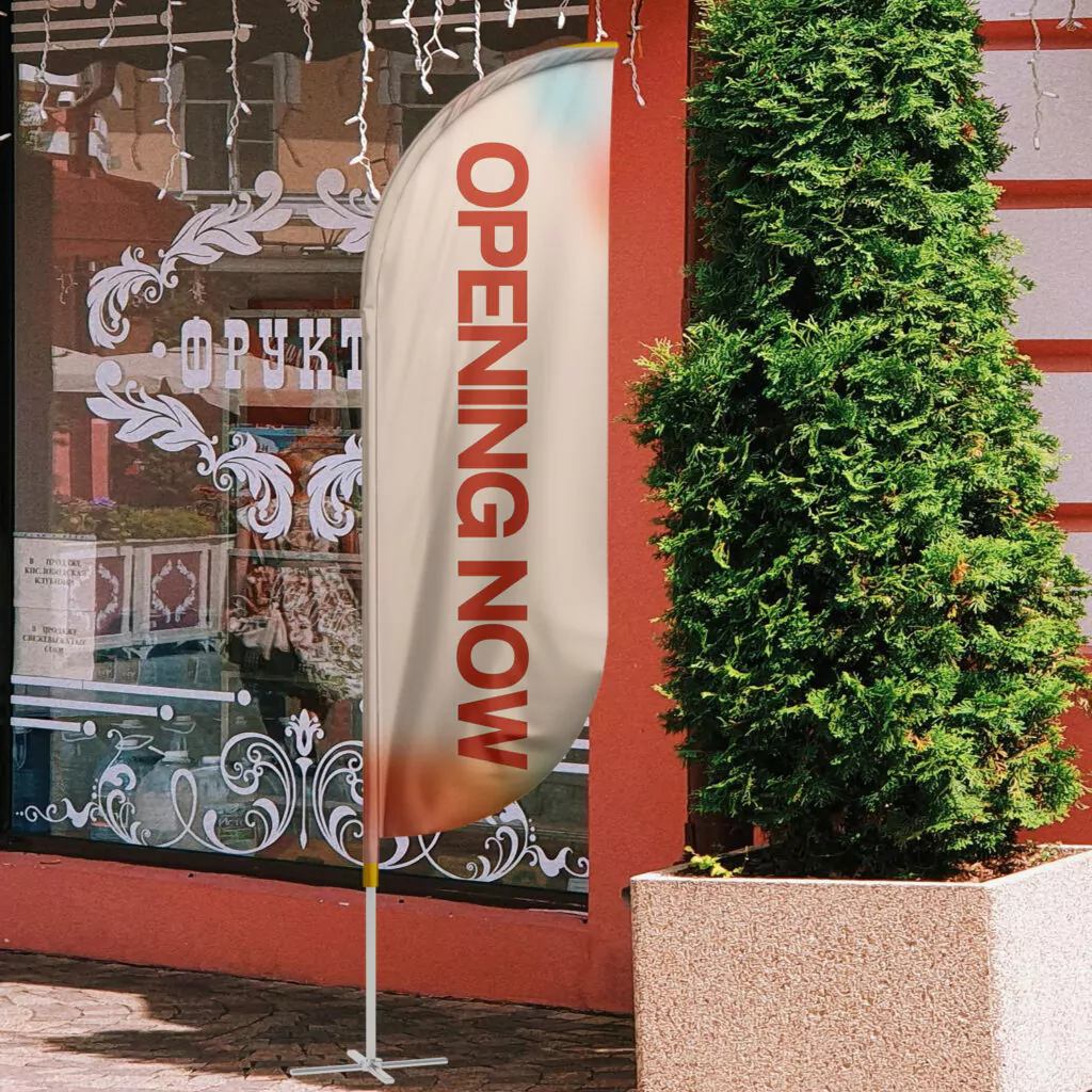 10 Reasons Why Custom Vertical Flags Are the Best Outdoor Advertising Solution 2 Custom vertical flags outdoor advertising with “Opening Now” text in front of a shop