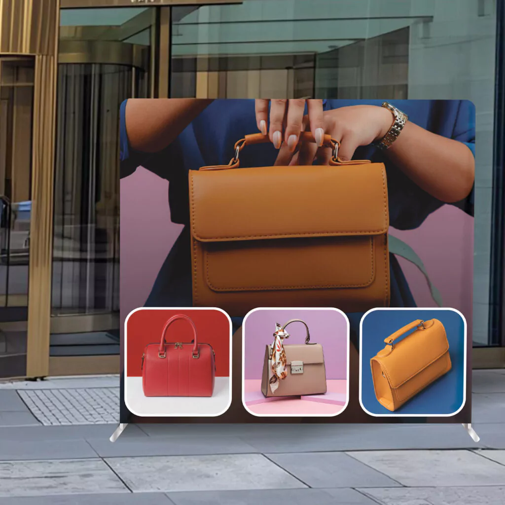 Custom Tension Fabric Display showcasing a high-resolution printed backdrop featuring luxury handbags in an outdoor setting.