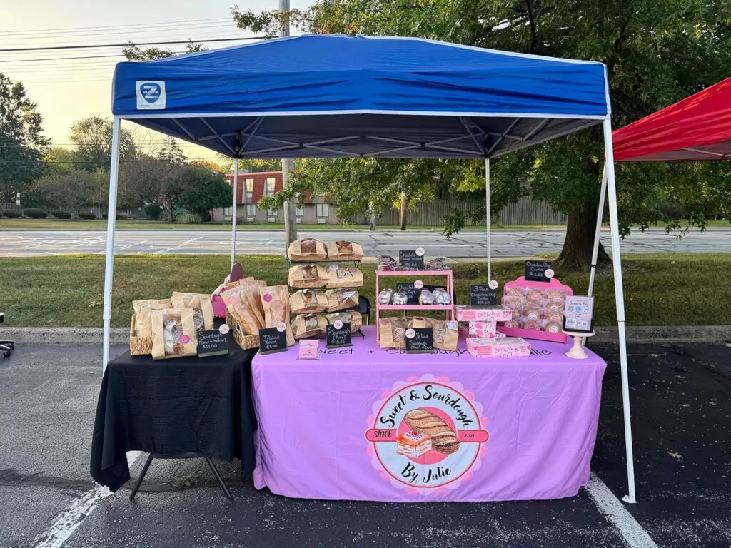 Outdoor event booth with a black spandex custom size table cover displaying snacks and supplies.